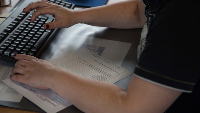 Ein Mensch gibt über eine Tastatur Daten in einen Computer ein.